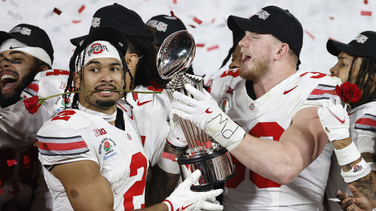 PASADENA, CALIFORNIA - JANUARY 01: Emeka Egbuka #2 and Jack Sawyer #33 of the Ohio State Buckeyes hold the Leishman Trophy after defeating the Oregon Ducks 41-21 during the Rose Bowl Game Presented by Prudential at Rose Bowl Stadium on January 01, 2025 in Pasadena, California.