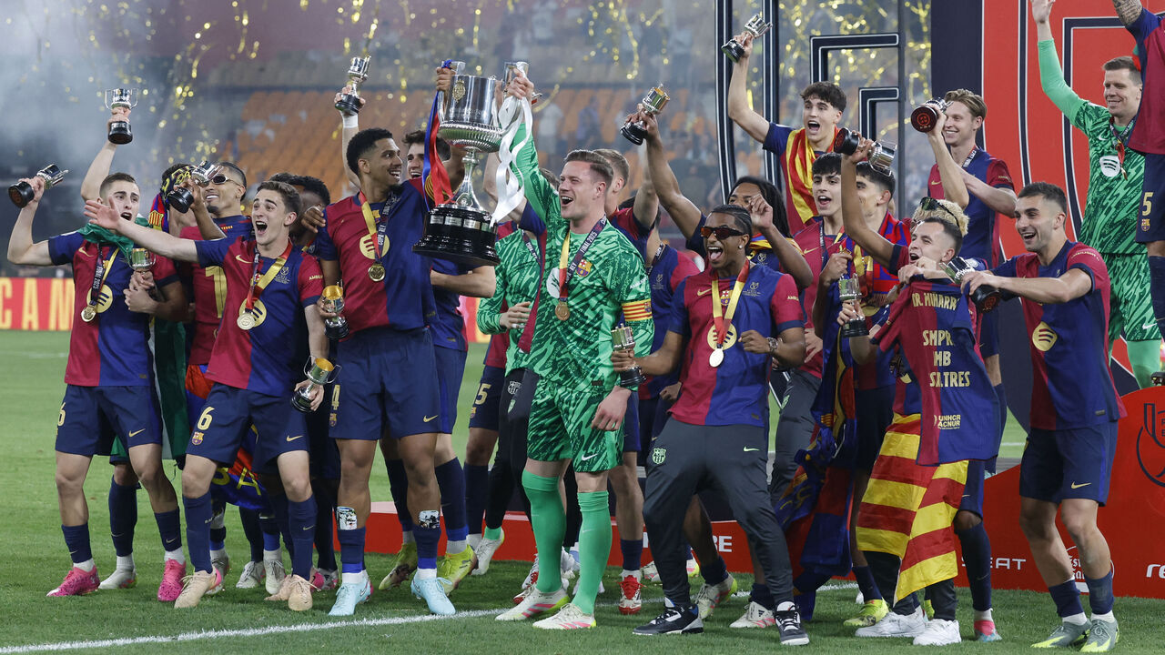 Barcelona's German goalkeeper #01 Marc-Andre Ter Stegen (CR) and Barcelona's Uruguayan defender #04 Ronald Federico Araujo da Silva (CL) raise their trophy as they celebrate with teammates winning the Spanish Cup, Copa del Rey (King's Cup) final football match between FC Barcelona and Real Madrid CF at La Cartuja stadium in Seville on April 26, 2025.