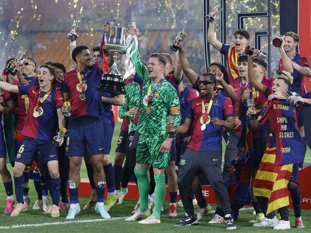 Barcelona's German goalkeeper #01 Marc-Andre Ter Stegen (CR) and Barcelona's Uruguayan defender #04 Ronald Federico Araujo da Silva (CL) raise their trophy as they celebrate with teammates winning the Spanish Cup, Copa del Rey (King's Cup) final football match between FC Barcelona and Real Madrid CF at La Cartuja stadium in Seville on April 26, 2025.