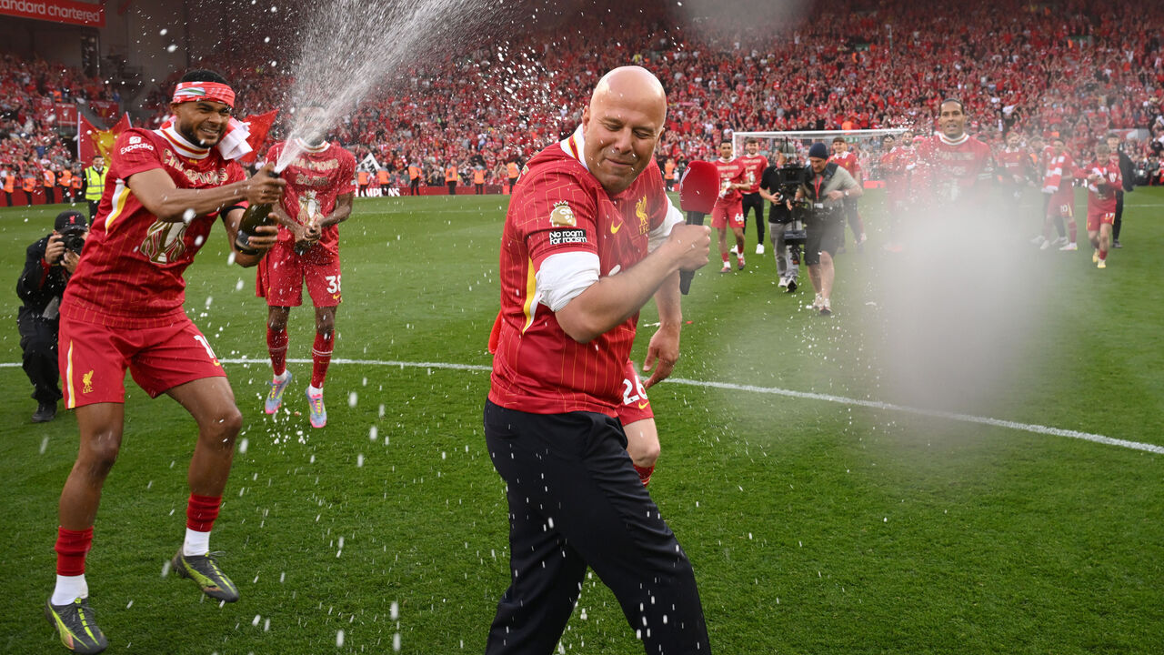 LIVERPOOL, ENGLAND - APRIL 27: (SUN OUT, SUN ON SUNDAY OUT) Cody Gakpo of Liverpool sprays drink over Arne Slot, Manger of Liverpool, as they celebrate the teams victory and confirmation of winning the Premier League title after the Premier League match between Liverpool FC and Tottenham Hotspur FC at Anfield on April 27, 2025 in Liverpool, England.
