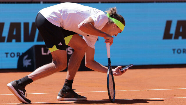 Germany's Alexander Zverev takes a picture with his mobile phone of the ball mark on the court after he disputed the referee decision during his match against Spain's Alejandro Davidovich Fokina during their 2025 ATP Tour Madrid Open tennis tournament third round singles match at the Caja Magica in Madrid, on April 27, 2025.