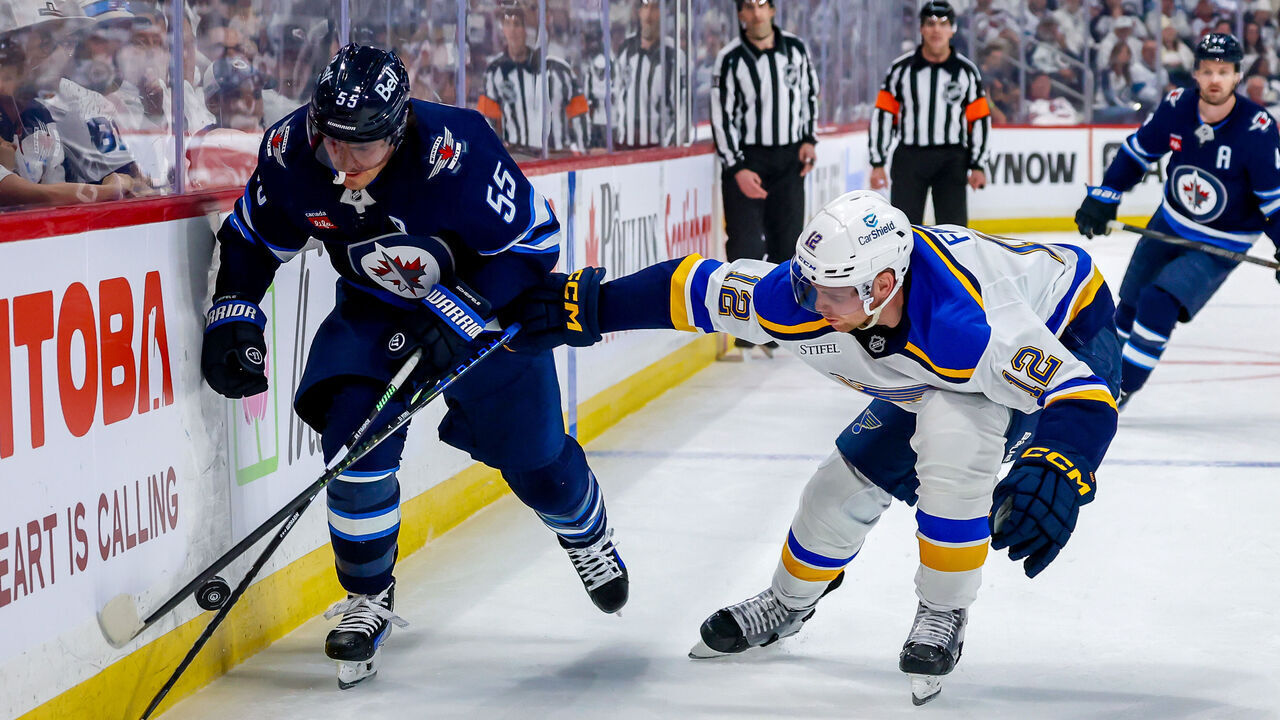 WINNIPEG, CANADA - APRIL 21: Mark Scheifele #55 of the Winnipeg Jets and Radek Faksa #12 of the St. Louis Blues chase the puck along the boards during second period action in Game Two of the First Round of the 2025 Stanley Cup Playoffs at Canada Life Centre on April 21, 2025 in Winnipeg, Manitoba, Canada.