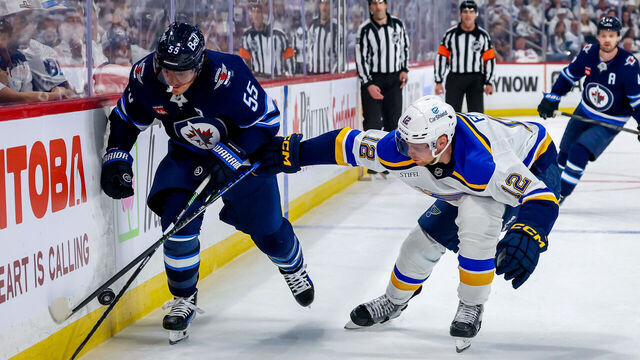 WINNIPEG, CANADA - APRIL 21: Mark Scheifele #55 of the Winnipeg Jets and Radek Faksa #12 of the St. Louis Blues chase the puck along the boards during second period action in Game Two of the First Round of the 2025 Stanley Cup Playoffs at Canada Life Centre on April 21, 2025 in Winnipeg, Manitoba, Canada.