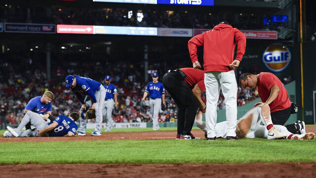 BOSTON, MASSACHUSETTS - MAY 07: Romy Gonzalez #23 of the Boston Red Sox (right) and Josh Smith #8 of the Texas Rangers are tended to after colliding on first base in the seventh inning at Fenway Park on May 07, 2025 in Boston, Massachusetts.