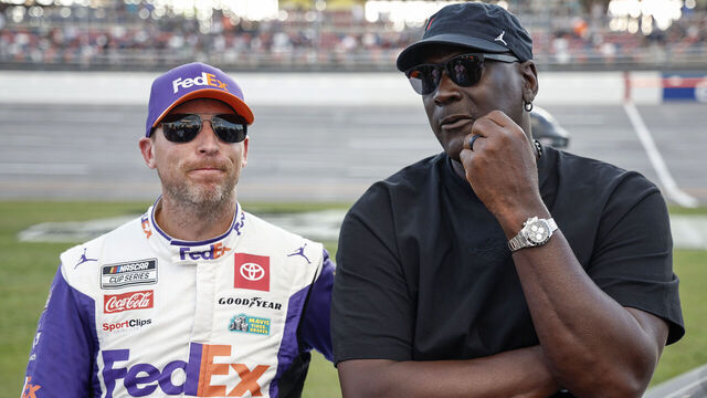 TALLADEGA, ALABAMA - OCTOBER 06: Co-owners of 23XI Racing, Denny Hamlin, driver of the #11 FedEx One Rate Toyota, and NBA Hall of Famer, Michael Jordan talk on the grid after the NASCAR Cup Series YellaWood 500 at Talladega Superspeedway on October 06, 2024 in Talladega, Alabama.