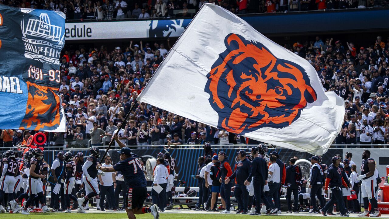 CHICAGO, IL - SEPTEMBER 08: A man holding a flag bearing the Chicago Bears logo runs across the field after the Chicago Bears scored a touchdown during the game between the Tennessee Titans and the Chicago Bears at Soldier Field on September 8, 2024 in Chicago, Illinois.