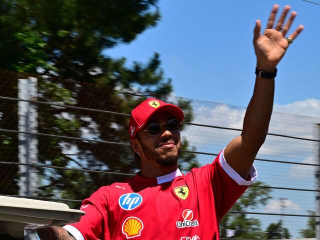 Ferrari's British driver Lewis Hamilton waves as he arrives on a golf cart before the 2025 Emilia Romagna Formula One Grand Prix at the Imola autodrome in Imola, on May 18, 2025.