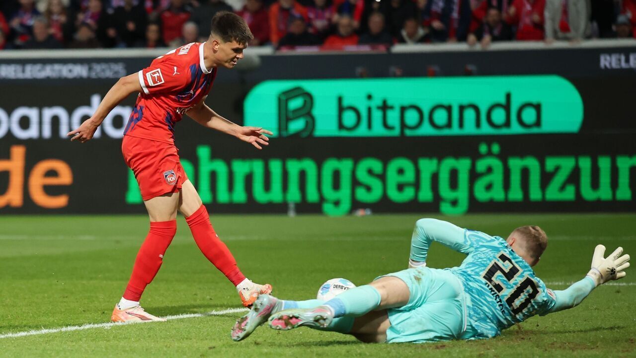 HEIDENHEIM, GERMANY - MAY 22: Mathias Honsak of Heidenheim shoots past Nicolas Kristof of Elvesberg to score his team's second goal during the Bundesliga playoffs first leg match between 1. FC Heidenheim 1846 and SV Elversberg at Voith-Arena on May 22, 2025 in Heidenheim, Germany.