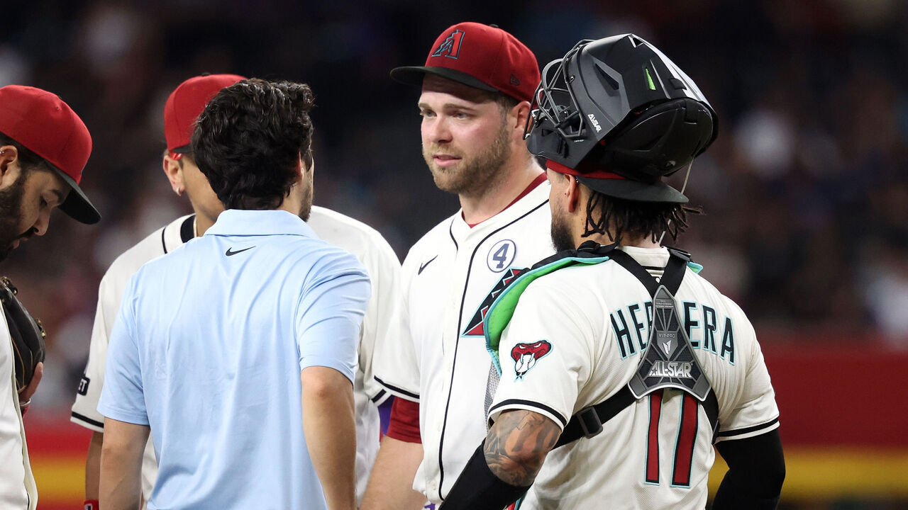 PHOENIX, ARIZONA - JUNE 01: Starting pitcher Corbin Burnes #39 of the Arizona Diamondbacks talks with with assistant athletic trainer Max Esposito before being removed from the game during the fifth inning against the Washington Nationals at Chase Field on June 01, 2025 in Phoenix, Arizona.