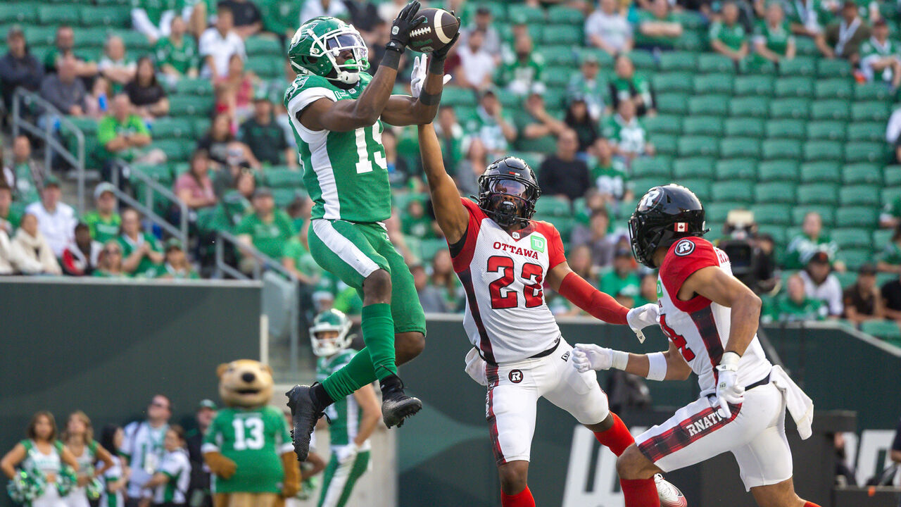 REGINA, CANADA - JUNE 5: Samuel Emilus #19 of the Saskatchewan Roughriders makes a leaping catch for a touchdown over Adrian Frye #22 of the Ottawa Redblacks in the first half of the game between the Ottawa Redblacks and Saskatchewan Roughriders at Mosaic Stadium on June 5, 2025 in Regina, Canada.
