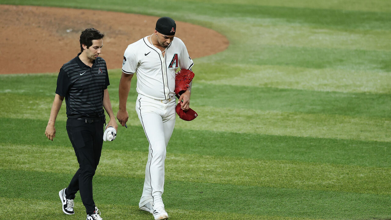 PHOENIX, ARIZONA - JUNE 09: Relief pitcher Justin Martinez #63 of the Arizona Diamondbacks walks off the field with a trainer after an injury during the ninth inning of the MLB game against the Seattle Mariners at Chase Field on June 09, 2025 in Phoenix, Arizona. The Diamondbacks defeated the Mariners 8-4 in 11 innings.