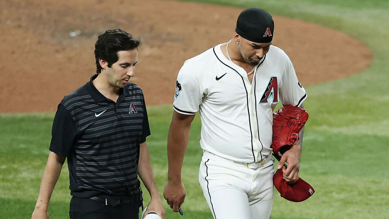 PHOENIX, ARIZONA - JUNE 09: Relief pitcher Justin Martinez #63 of the Arizona Diamondbacks walks off the field with a trainer after an injury during the ninth inning of the MLB game against the Seattle Mariners at Chase Field on June 09, 2025 in Phoenix, Arizona. The Diamondbacks defeated the Mariners 8-4 in 11 innings.