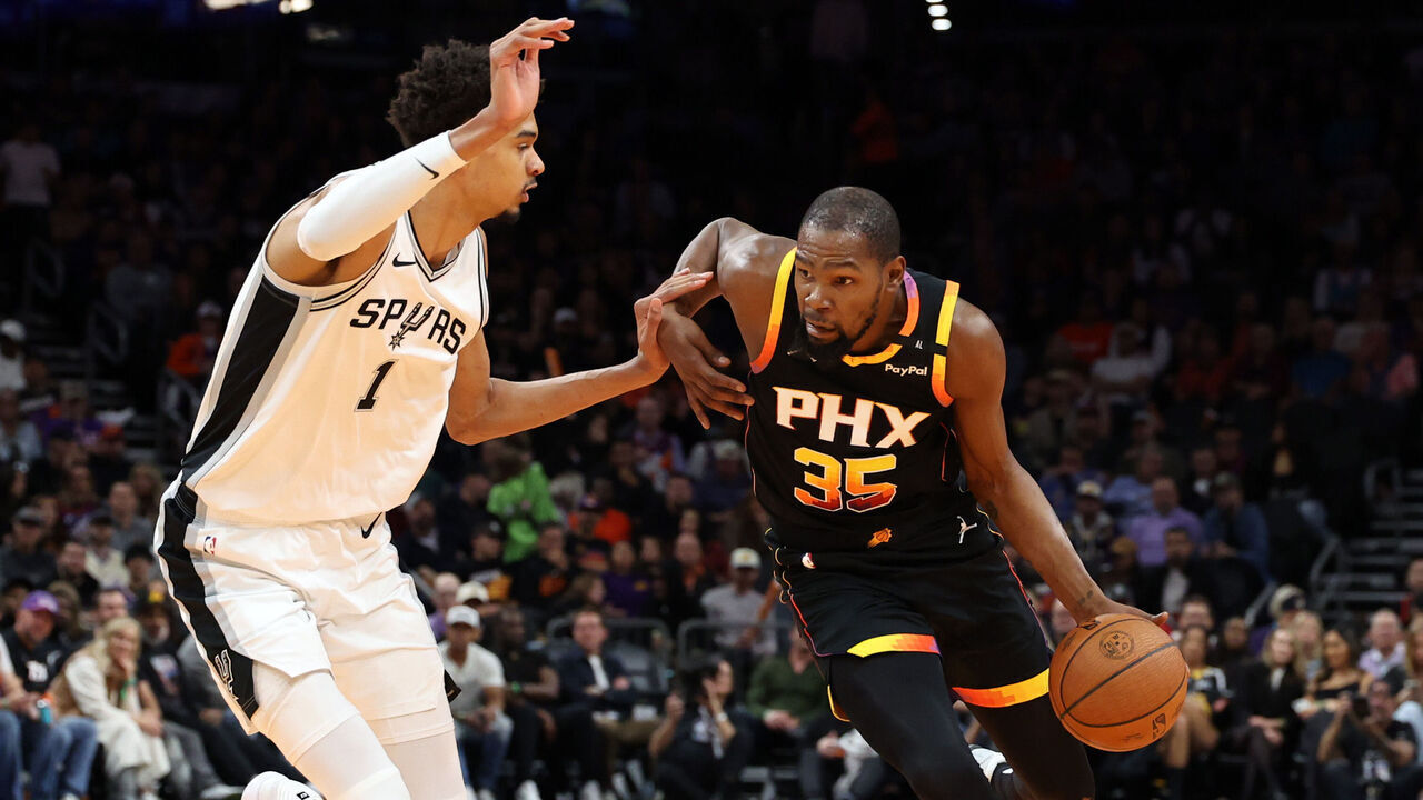 PHOENIX, ARIZONA - DECEMBER 03: Kevin Durant #35 of the Phoenix Suns drives against Victor Wembanyama #1 of the San Antonio Spurs during the first half of the Emirates NBA Cup game at Footprint Center on December 03, 2024 in Phoenix, Arizona. The Suns defeated the Spurs 104-93.