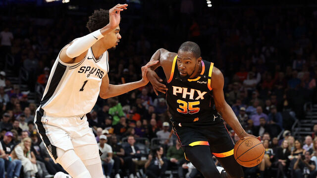 PHOENIX, ARIZONA - DECEMBER 03: Kevin Durant #35 of the Phoenix Suns drives against Victor Wembanyama #1 of the San Antonio Spurs during the first half of the Emirates NBA Cup game at Footprint Center on December 03, 2024 in Phoenix, Arizona. The Suns defeated the Spurs 104-93.