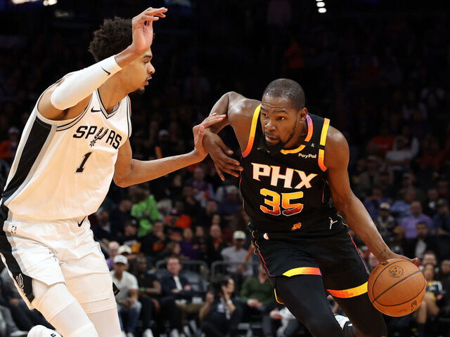 PHOENIX, ARIZONA - DECEMBER 03: Kevin Durant #35 of the Phoenix Suns drives against Victor Wembanyama #1 of the San Antonio Spurs during the first half of the Emirates NBA Cup game at Footprint Center on December 03, 2024 in Phoenix, Arizona. The Suns defeated the Spurs 104-93.