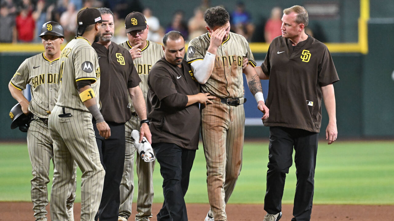 PHOENIX, AZ - JUNE 14: Jackson Merrill #3 of the San Diego Padres is escorted off the field after being tagged in the head while stealing second base in the seventh inning during the game between the San Diego Padres and the Arizona Diamondbacks at Chase Field on Saturday, June 14, 2025 in Phoenix, Arizona.