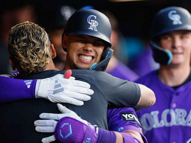 DENVER, CO - JULY 19: Ezequiel Tovar #14 of the Colorado Rockies smiles and is congratulated by Orlando Arcia #11 in the dugout after hitting a three-run home run as Mickey Moniak #22 looks on in the fifth inning against the Minnesota Twins at Coors Field on July 19, 2025 in Denver, Colorado.