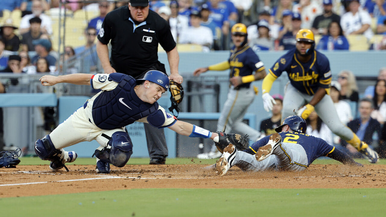 LOS ANGELES, CALIFORNIA - JULY 19: Catcher Will Smith #16 of the Los Angeles Dodgers stretches but unable to tag out Brice Turang #2 of the Milwaukee Brewers at home plate as he scores on a two run double by William Contreras #24 of the Milwaukee Brewers during the third inning at Dodger Stadium on July 19, 2025 in Los Angeles, California.
