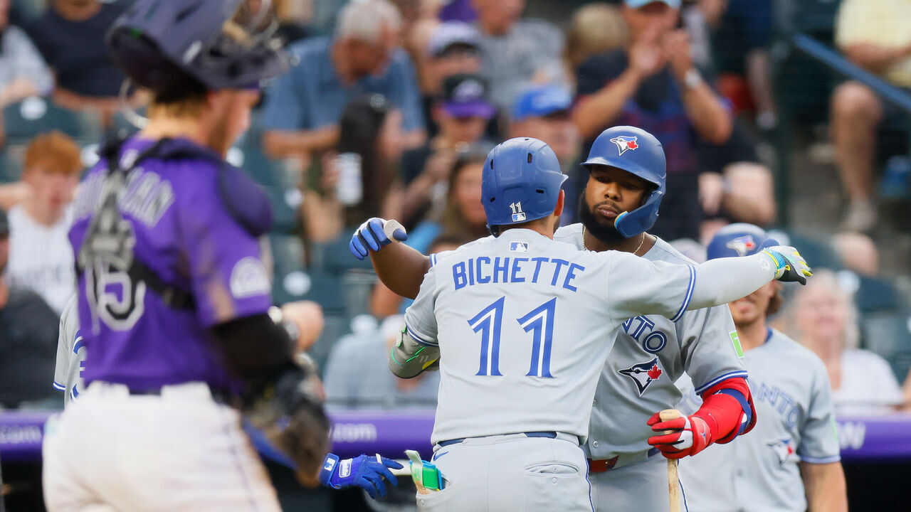 DENVER, CO - AUGUST 4: Bo Bichette #11 of the Toronto Blue Jays gets a hug from Vladimir Guerrero Jr. #27 after hitting a two run home run in the third inning as catcher Hunter Goodman #15 of the Colorado Rockies looks on at Coors Field on August 4, 2025 in Denver, Colorado.