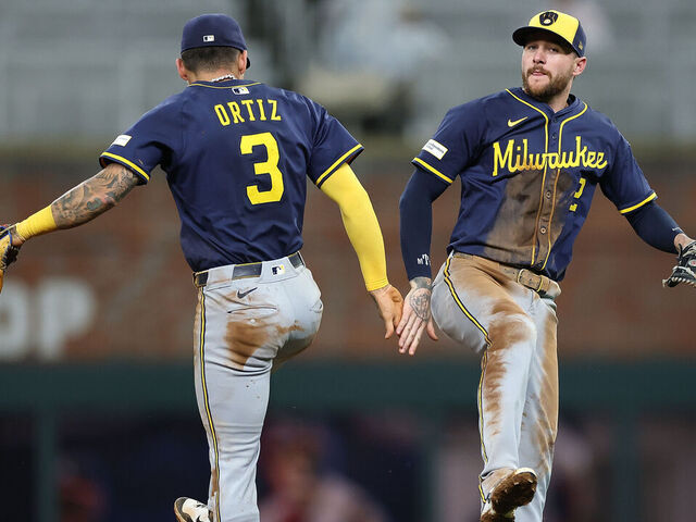 ATLANTA, GEORGIA - AUGUST 05: Joey Ortiz #3 and Brice Turang #2 of the Milwaukee Brewers react after their 7-2 win over the Atlanta Braves at Truist Park on August 05, 2025 in Atlanta, Georgia.