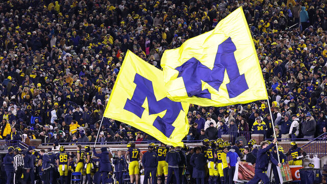 ANN ARBOR, MI - NOVEMBER 23: Michigan cheerleaders run up and down the field carrying giant flags with the Michigan block "M" logo after a touchdown during the fourth quarter of a regular season Big Ten Conference college football game between the Northwestern Wildcats and the Michigan Wolverines on November 23, 2024 at Michigan Stadium in Ann Arbor, Michigan.