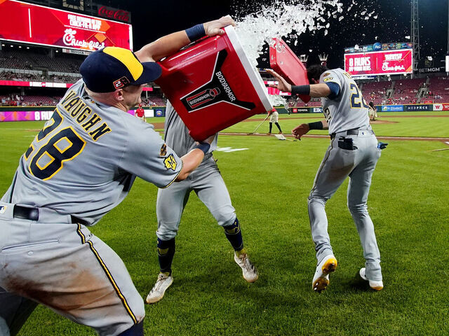 CINCINNATI, OHIO - AUGUST 15: Andrew Vaughn #28 and Caleb Durbin #21 of the Milwaukee Brewers attempt to dump ice on teammate Christian Yelich #22 after the game against the Cincinnati Reds at Great American Ball Park on August 15, 2025 in Cincinnati, Ohio. Milwaukee Brewers won 10-8.