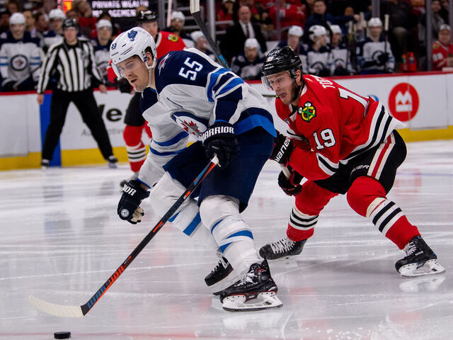 CHICAGO, IL - APRIL 01: Winnipeg Jets center Mark Scheifele (55) controls the puck against Chicago Blackhawks center Jonathan Toews (19) during a game between the Winnipeg Jets and the Chicago Blackhawks on April 1, 2019, at the United Center in Chicago, IL.