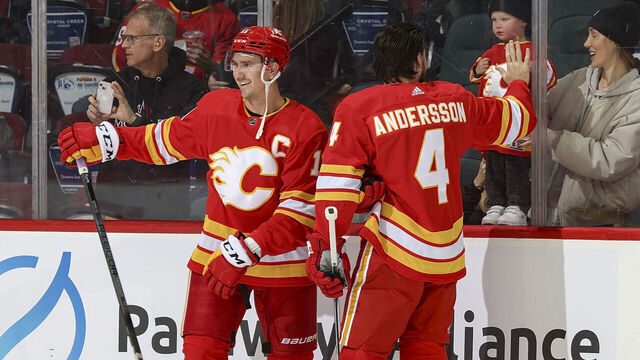 CALGARY, AB - NOVEMBER 1: Rasmus Andersson #4 and Mikael Backlund #11 of the Calgary Flames say hello to family during warmup prior to the game against the Dallas Stars at Scotiabank Saddledome on November 1, 2023 in Calgary, Alberta, Canada.