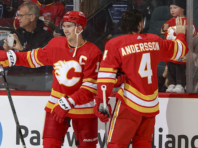 CALGARY, AB - NOVEMBER 1: Rasmus Andersson #4 and Mikael Backlund #11 of the Calgary Flames say hello to family during warmup prior to the game against the Dallas Stars at Scotiabank Saddledome on November 1, 2023 in Calgary, Alberta, Canada.