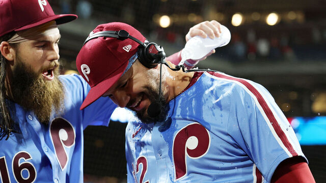 PHILADELPHIA, PENNSYLVANIA - AUGUST 28: Brandon Marsh #16 pours a water bottle on Kyle Schwarber #12 of the Philadelphia Phillies during his post game interview after a 19-4 win over the Atlanta Braves at Citizens Bank Park on August 28, 2025 in Philadelphia, Pennsylvania. Kyle Schwarber hit four home runs during the game.
