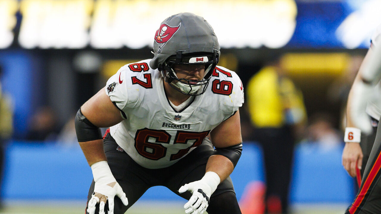 INGLEWOOD, CALIFORNIA - DECEMBER 15: Luke Goedeke #67 of the Tampa Bay Buccaneers wears a Guardian Cap in an offensive stance during the second half against the Los Angeles Chargers at SoFi Stadium on December 15, 2024 in Inglewood, California.