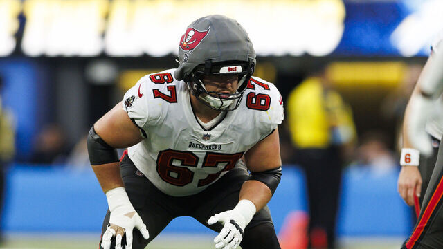 INGLEWOOD, CALIFORNIA - DECEMBER 15: Luke Goedeke #67 of the Tampa Bay Buccaneers wears a Guardian Cap in an offensive stance during the second half against the Los Angeles Chargers at SoFi Stadium on December 15, 2024 in Inglewood, California.