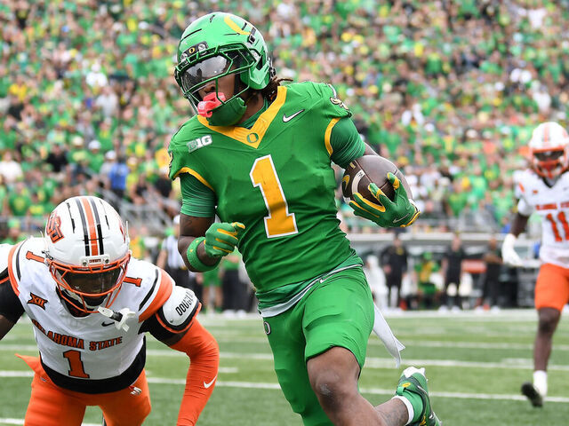 EUGENE, OR - SEPTEMBER 06: Oregon Ducks wide receiver Dakorien Moore (1) scores on a 25-yard touchdown run against Oklahoma State Cowboys corner back JK Johnson (1) in the second quarter during a college football game between the Oklahoma State Cowboys and the Oregon Ducks on September 6, 2025, at Autzen Stadium in Eugene, Oregon.