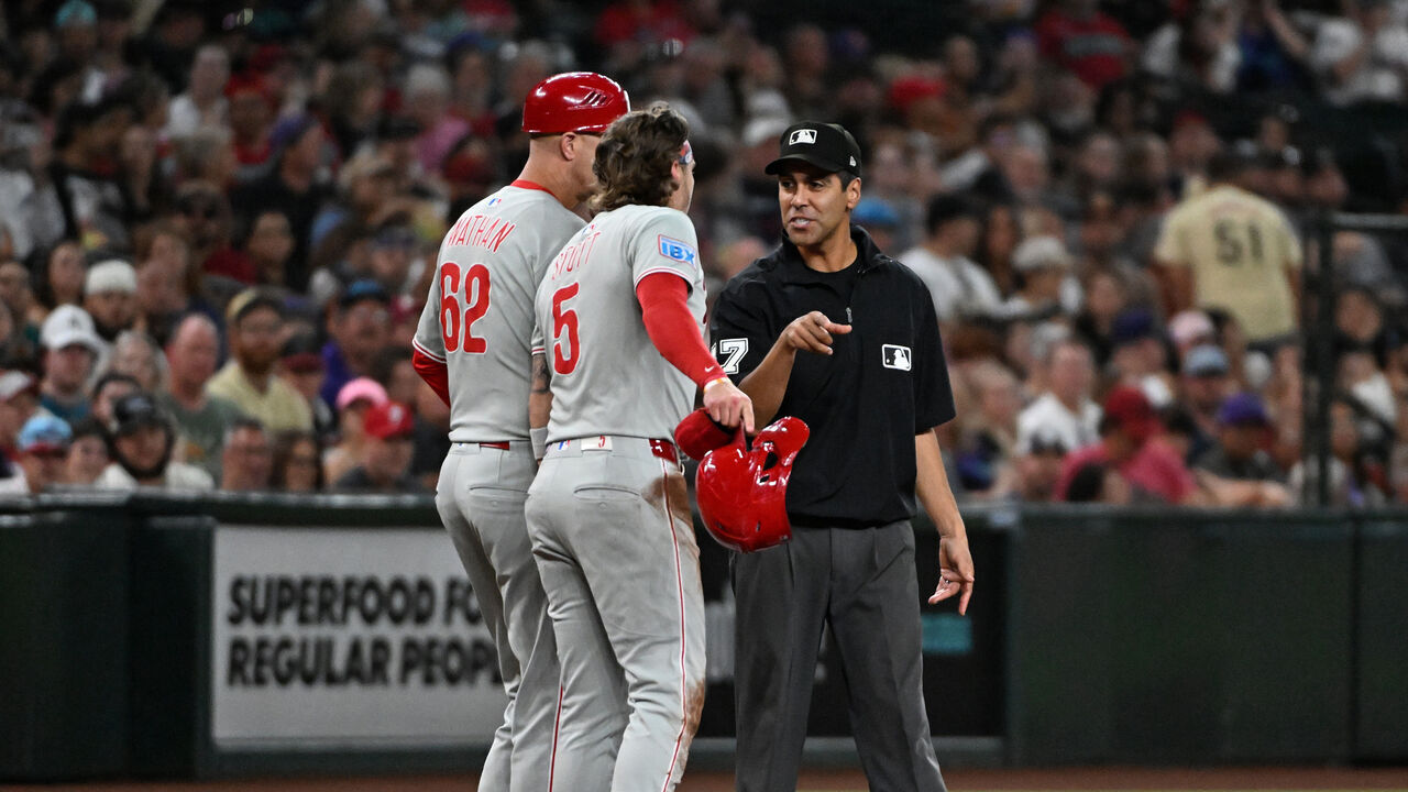 PHOENIX, ARIZONA - SEPTEMBER 20: Bryson Stott #5 and third base coach Dusty Wathan #62 of the Philadelphia Phillies argue with third base umpire Gabe Morales #47 during the fifth inning against the Arizona Diamondbacks at Chase Field on September 20, 2025 in Phoenix, Arizona.