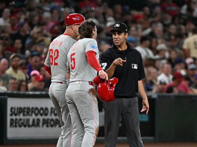 PHOENIX, ARIZONA - SEPTEMBER 20: Bryson Stott #5 and third base coach Dusty Wathan #62 of the Philadelphia Phillies argue with third base umpire Gabe Morales #47 during the fifth inning against the Arizona Diamondbacks at Chase Field on September 20, 2025 in Phoenix, Arizona.