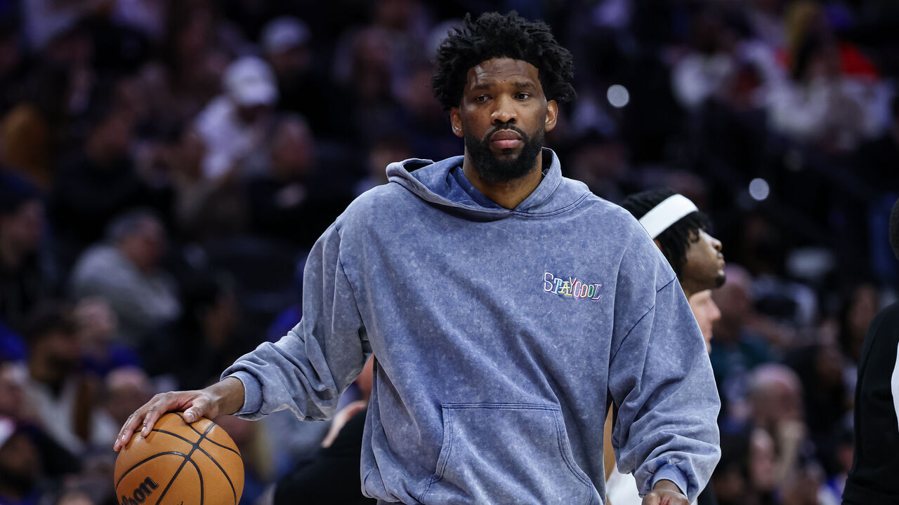 PHILADELPHIA, PENNSYLVANIA - MARCH 01: Joel Embiid #21 of the Philadelphia 76ers dribbles a ball while wearing street clothes on the bench during the second half of the game against the Golden State Warriors at the Wells Fargo Center on March 1, 2025 in Philadelphia, Pennsylvania.