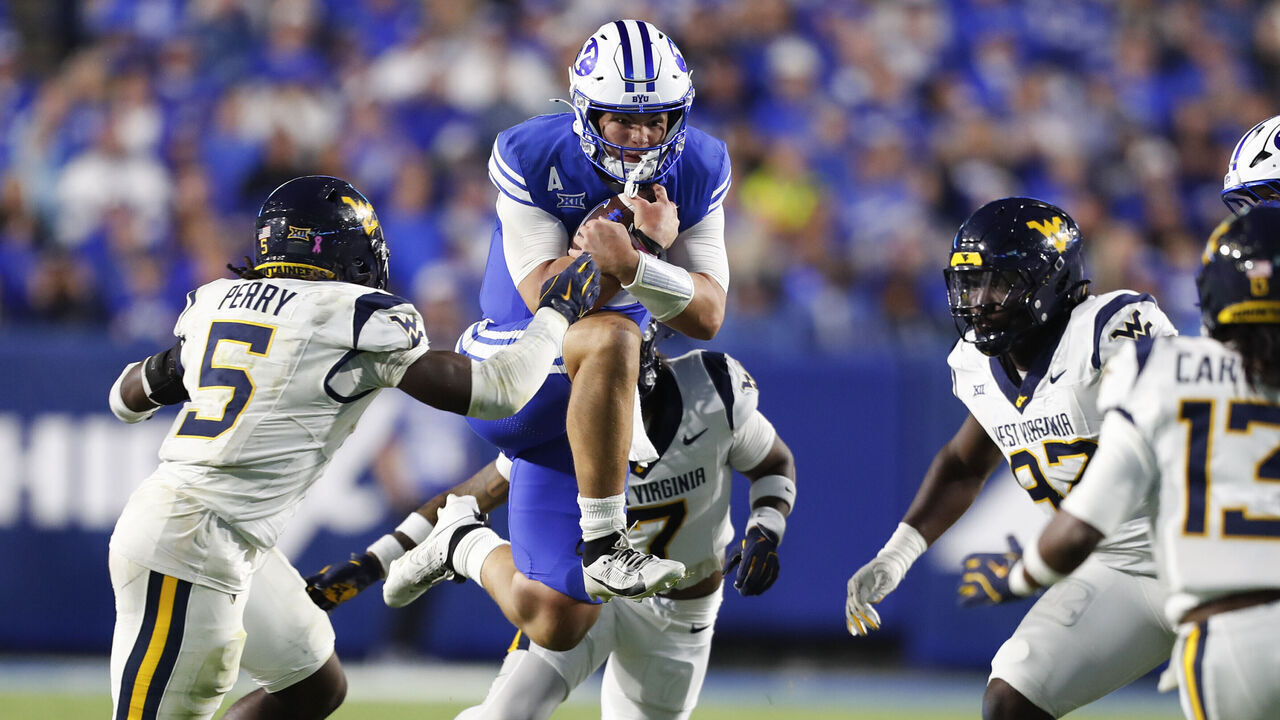 PROVO, UT - OCTOBER 3: Bear Bachmeier #47 of the Brigham Young Cougars rushes the ball against Fred Perry #5, Israel Boyce #7, Adam Tomczyk #97, and Derek Carter Jr., #13 of the West Virginia Mountaineers during the second half their game at LaVell Edwards Stadium on October 3, 2025 at Provo, Utah.