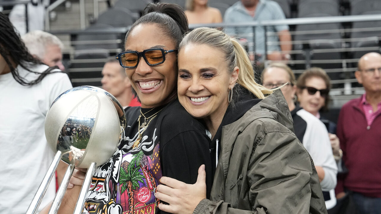LAS VEGAS, NEVADA - OCTOBER 12: A'ja Wilson (L) #22 and head coach Becky Hammon of the Las Vegas Aces embrace with the 2025 WNBA championship trophy on the field before a game between Tennessee Titans and Las Vegas Raiders at Allegiant Stadium on October 12, 2025 in Las Vegas, Nevada.