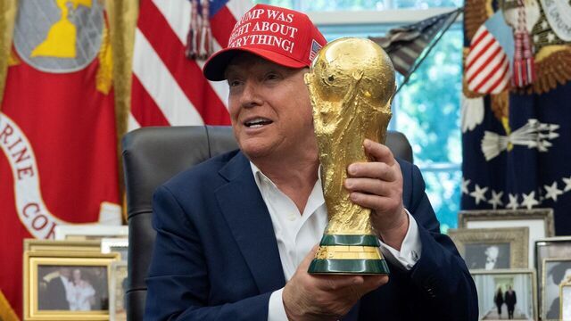US President Donald Trump holds the World Cup trophy in the Oval Office of the White House in Washington, DC, on August 22, 2025. Trump announced the 2026 World Cup draw will be held on December 5 at Washington's Kennedy Center.