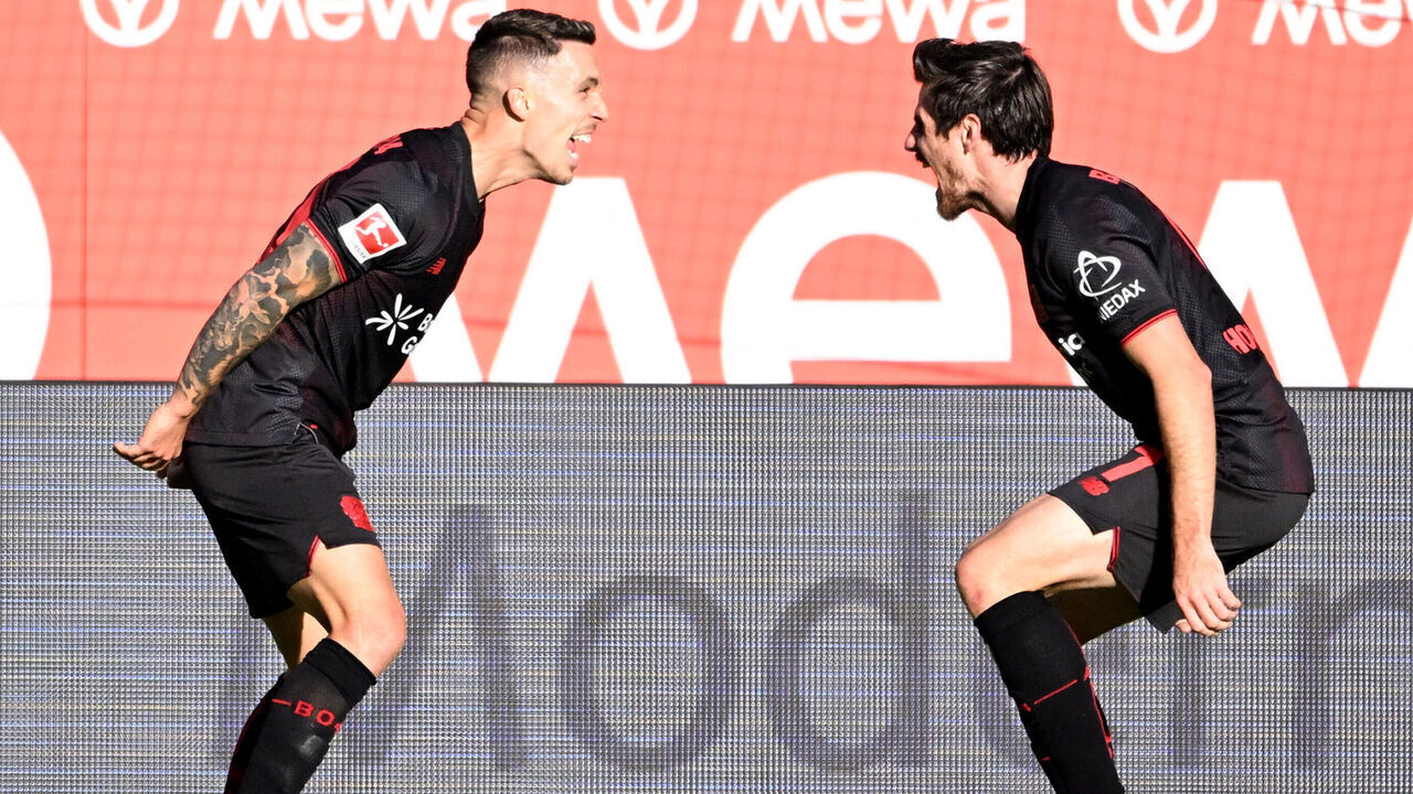 Bayer Leverkusen's Spanish defender #20 Alejandro Grimaldo (L) celebrates with Bayer Leverkusen's German midfielder #07 Jonas Hofmann after scoring the 1-3 goal during the German first division Bundesliga football match Mainz 05 v Bayer 04 Leverkusen in Mainz, western Germany on October 18, 2025.