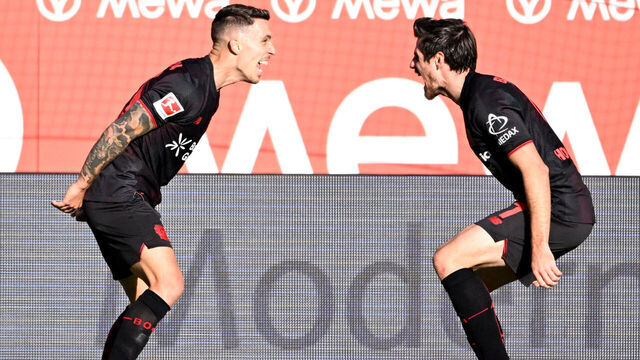 Bayer Leverkusen's Spanish defender #20 Alejandro Grimaldo (L) celebrates with Bayer Leverkusen's German midfielder #07 Jonas Hofmann after scoring the 1-3 goal during the German first division Bundesliga football match Mainz 05 v Bayer 04 Leverkusen in Mainz, western Germany on October 18, 2025.