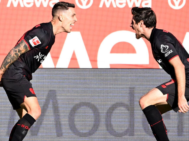 Bayer Leverkusen's Spanish defender #20 Alejandro Grimaldo (L) celebrates with Bayer Leverkusen's German midfielder #07 Jonas Hofmann after scoring the 1-3 goal during the German first division Bundesliga football match Mainz 05 v Bayer 04 Leverkusen in Mainz, western Germany on October 18, 2025.