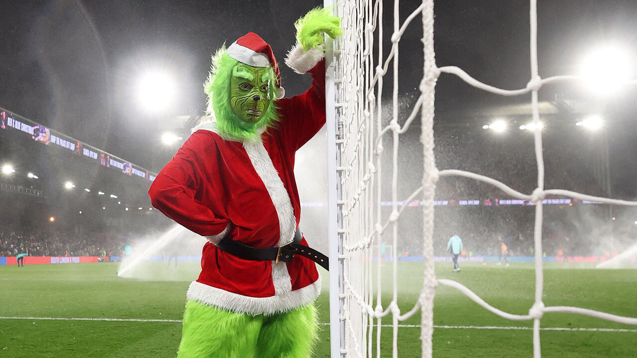 LONDON, ENGLAND - DECEMBER 21: A performer, dressed as the Grinch, poses for a photograph as they walk around the pitch at half time during the Premier League match between Crystal Palace FC and Arsenal FC at Selhurst Park on December 21, 2024 in London, England.