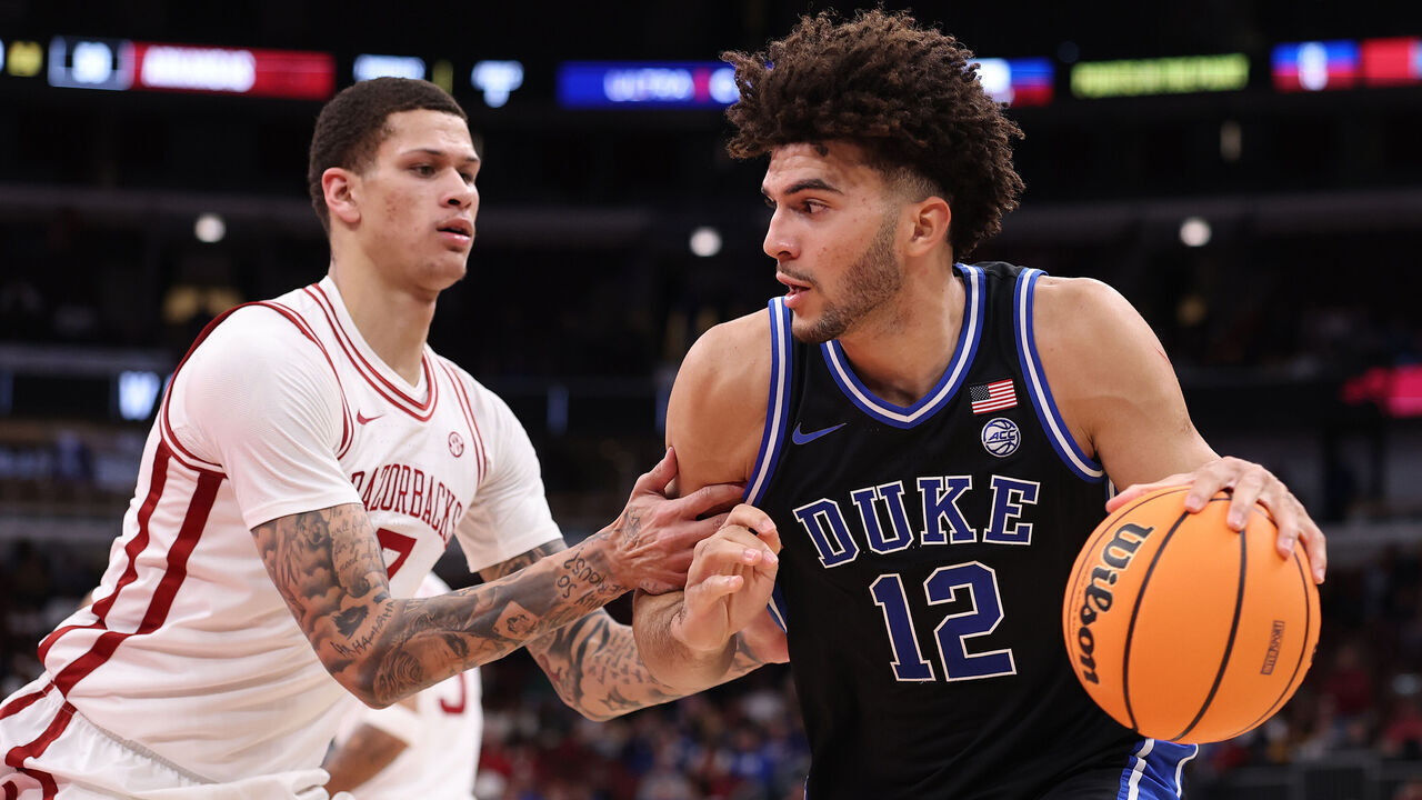 CHICAGO, ILLINOIS - NOVEMBER 27: Cameron Boozer #12 of the Duke Blue Devils drives to the basket against Trevon Brazile #7 of the Arkansas Razorbacks during the second half of the CBS Thanksgiving Classic at the United Center on November 27, 2025 in Chicago, Illinois.