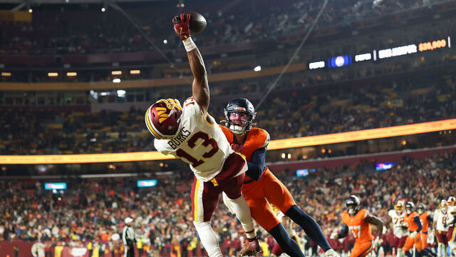 LANDOVER, MARYLAND - NOVEMBER 30: Treylon Burks #13 of the Washington Commanders catches a pass for a touchdown against Riley Moss #21 of the Denver Broncos during the third quarter at Northwest Stadium on November 30, 2025 in Landover, Maryland.