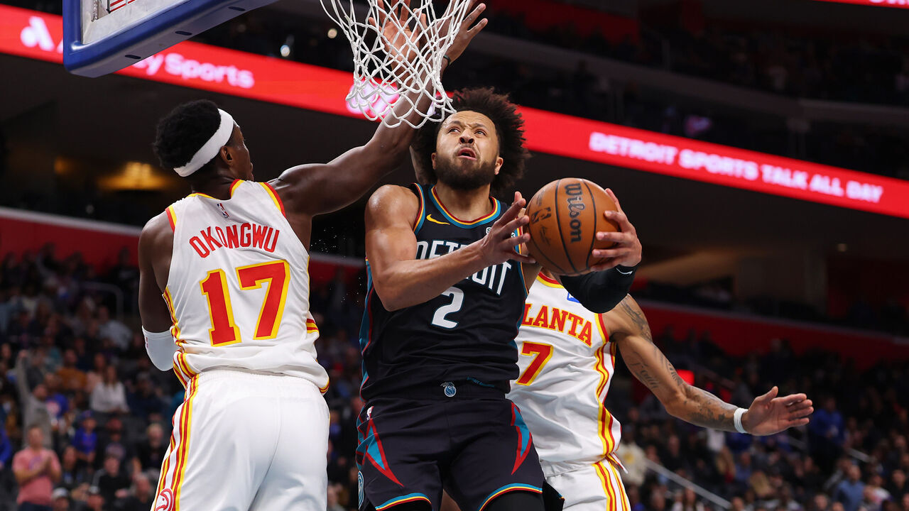 DETROIT, MICHIGAN - DECEMBER 01: Cade Cunningham #2 of the Detroit Pistons drives to the basket between Onyeka Okongwu #17 and Nickeil Alexander-Walker #7 of the Atlanta Hawks during the second half at Little Caesars Arena on December 01, 2025 in Detroit, Michigan.
