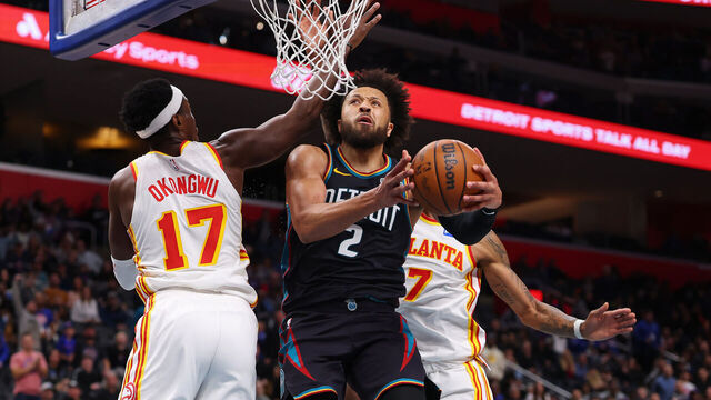 DETROIT, MICHIGAN - DECEMBER 01: Cade Cunningham #2 of the Detroit Pistons drives to the basket between Onyeka Okongwu #17 and Nickeil Alexander-Walker #7 of the Atlanta Hawks during the second half at Little Caesars Arena on December 01, 2025 in Detroit, Michigan.