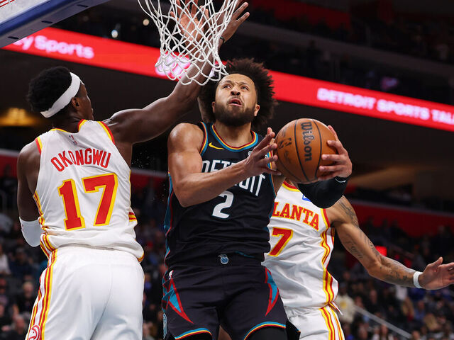DETROIT, MICHIGAN - DECEMBER 01: Cade Cunningham #2 of the Detroit Pistons drives to the basket between Onyeka Okongwu #17 and Nickeil Alexander-Walker #7 of the Atlanta Hawks during the second half at Little Caesars Arena on December 01, 2025 in Detroit, Michigan.