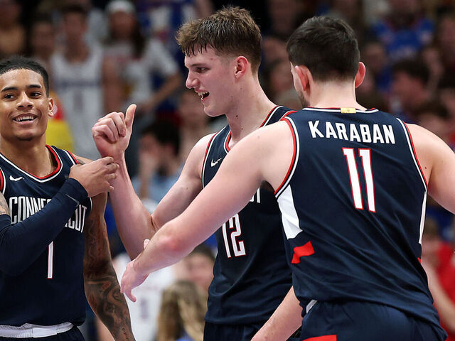 LAWRENCE, KANSAS - DECEMBER 02: Solo Ball #1, Eric Reibe #12 and Alex Karaban #11 of the UConn Huskies celebrate during the game against the Kansas Jayhawks at Allen Fieldhouse on December 02, 2025 in Lawrence, Kansas.