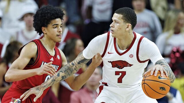 FAYETTEVILLE, ARKANSAS - DECEMBER 03: Trevon Brazile #7 of the Arkansas Razorbacks drives to the basket in the second half against Mikel Brown Jr. #0 of the Louisville Cardinals at Bud Walton Arena on December 03, 2025 in Fayetteville, Arkansas. The Razorbacks defeated the Cardinals 89-80.